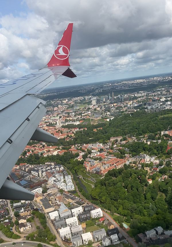 Aerial view of Vilnius, Lithuania, with a Turkish Airlines plane wing in the foreground.