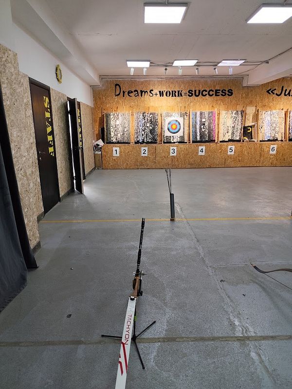Indoor archery range with target boards and archery equipment set up for practice.