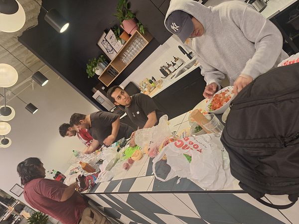 A group of friends is gathered in a kitchen preparing food together.