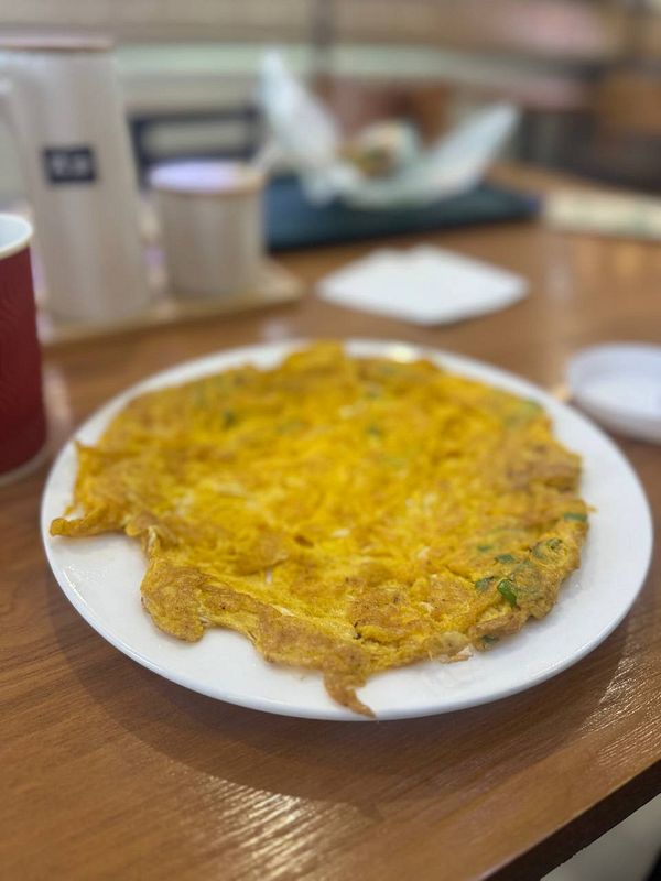 A plate of omelette is presented on a wooden table.