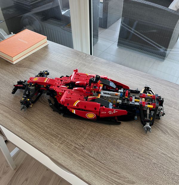 A partially assembled Lego model of a Formula 1 car is displayed on a wooden table.