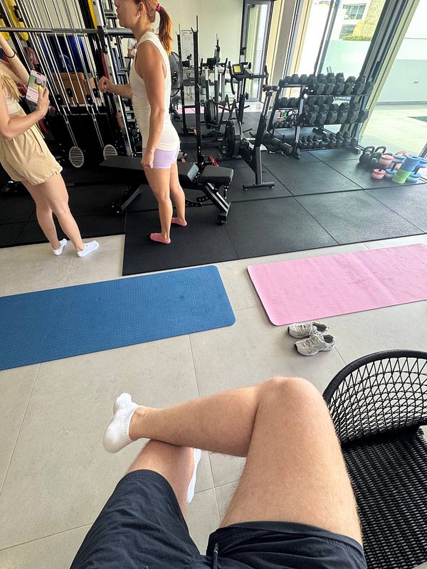 A personal training session is taking place in a well-equipped gym.