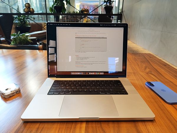 A workspace featuring a laptop, a smartphone, and a reflective surface.