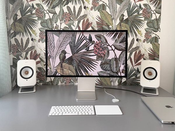 A modern workspace with a computer displaying wallpaper of a mountain and sea scenery.