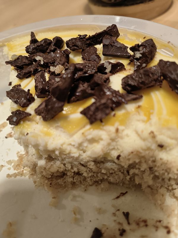 A close-up view of a chocolate lemon cheesecake with a portion missing.
