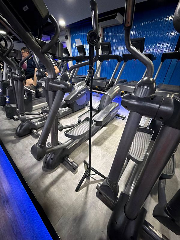 A muscular man lifting dumbbells in a gym setting with motivational text and navigation icons.