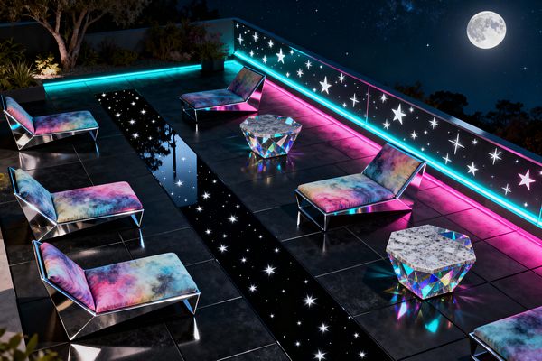 A rooftop patio at night under a full moon features five low-slung chaise lounges with polished metal frames and galaxy-print cushions in pink, teal, purple, and blue. Two faceted, iridescent side tables with pale marbled tops sit between the chairs. The charcoal tiled floor includes a glossy black glass strip sprinkled with star-like lights. A railing with star motifs is backlit by continuous neon cyan and magenta LEDs, with planters and a small tree along the edges.