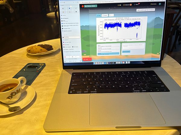A laptop is open on a table, displaying a data visualization interface alongside a cup of coffee and a plate of cookies.
