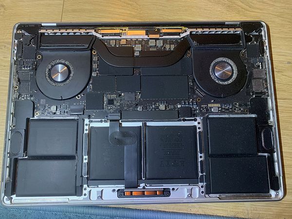 The image displays the internal components of a laptop, showcasing dust and debris accumulation.