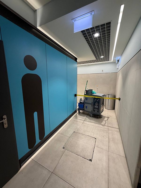 Photo of a blocked toilet door in Lisbon Airport arrivals area with a 17-minute cleaning notice.