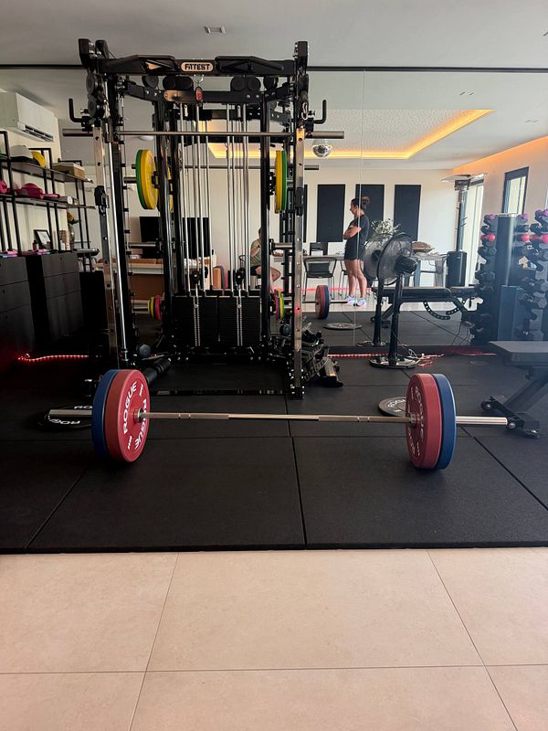 A gym workout setup featuring a barbell loaded with weight plates in a squat rack, ready for leg day exercises.