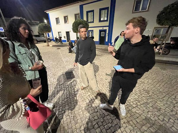 A group of friends is engaged in conversation at night during the Beerceira festival.