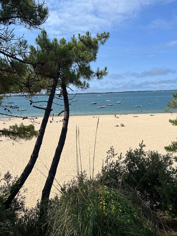 A scenic view of a French beach with sandy shores and boats in the water.