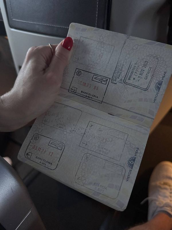 A hand holds an open passport displaying several faded stamps.