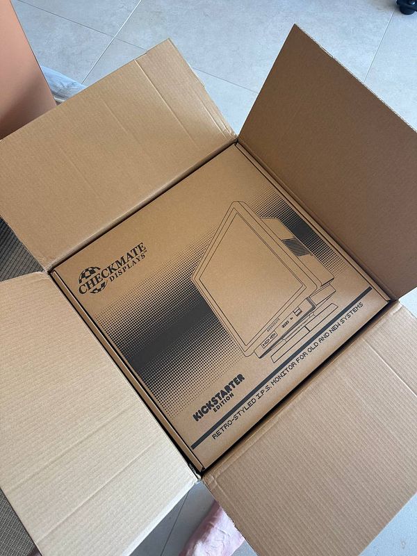 A retro-style monitor box is seen inside an open cardboard box.