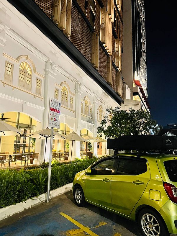 A vibrant green car is parked in front of a stylish building at night.