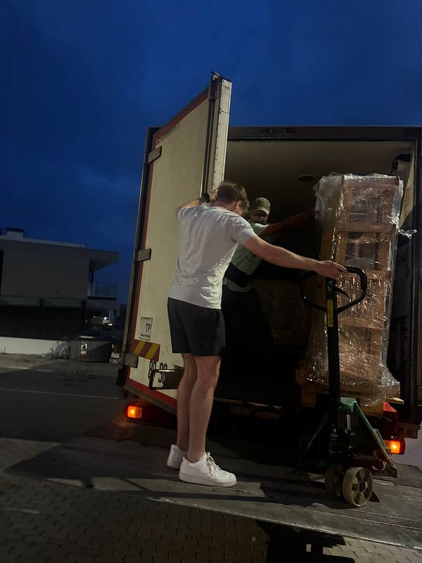 A group of individuals is unloading a large stone table from a truck at night.