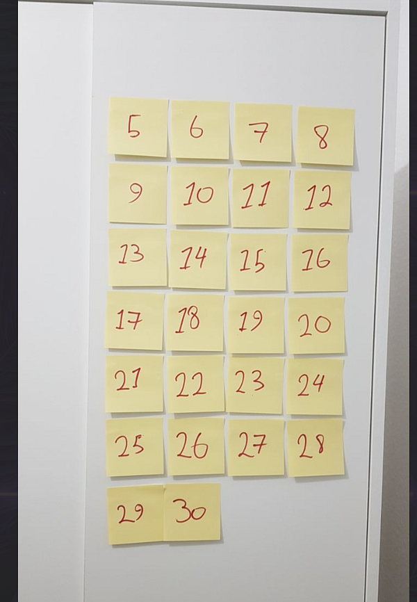 A grid of yellow sticky notes displaying numbers from 5 to 30 arranged on a white surface.
