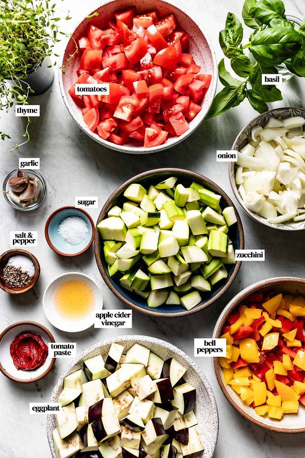 A vibrant display of fresh vegetables and ingredients arranged in bowls for a cooking preparation.