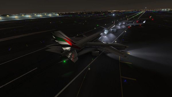 A nighttime view of an airport runway featuring multiple aircraft illuminated by runway lights.