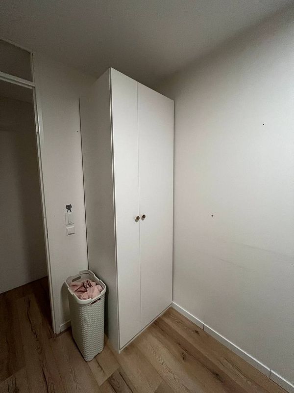 A newly assembled white closet stands in a minimalist room.