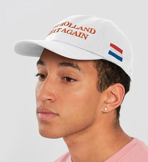 A young man is wearing a white cap with the phrase 'Make Holland Great Again' and a small Dutch flag.