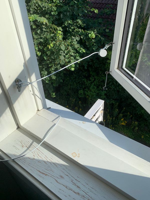 A window with a makeshift setup for holding it open using a string and a hook.