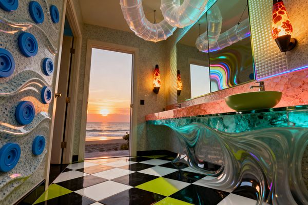 A psychedelic laundry space with a green vessel sink on a glass counter, set over a wavy iridescent acrylic base, glows with LED lighting. Backlit pink stone, mirrored cabinets, black-and-white checkerboard flooring with neon-lime tiles, translucent ceiling ducting, and two orange-red lava lamps frame an open doorway overlooking a sunset beach.