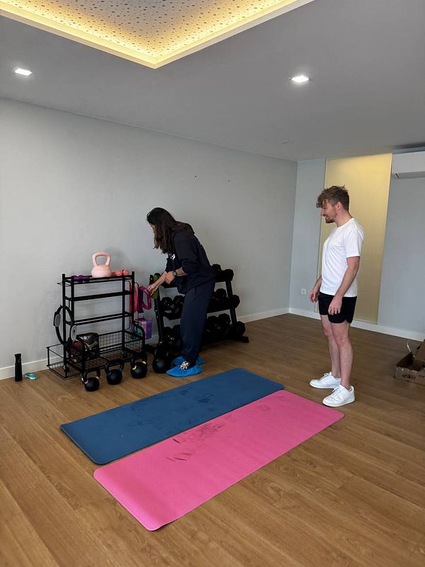 A personal trainer and a client are preparing for a workout in a home gym.