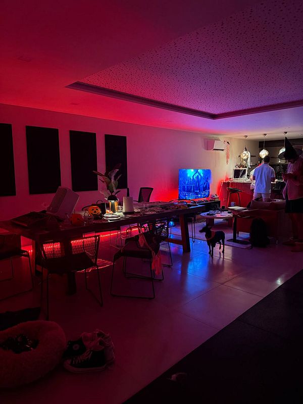 A cozy indoor space is decorated with Halloween-themed lighting and furniture, preparing for a BBQ party.