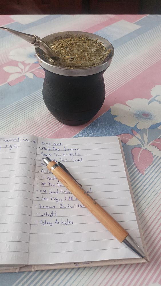 Photograph of a wooden table with two mate gourds and a small loaf of bread, arranged for a casual social gathering.