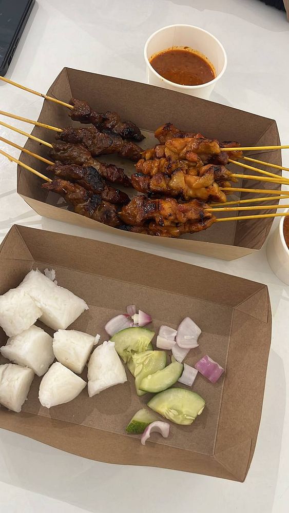 Close-up of skewered satay with charred bits served on a white plate.