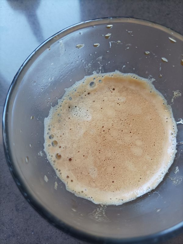 A close-up view of a glass containing a frothy coffee beverage.