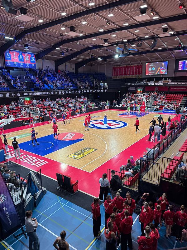 Action shot of a basketball game between Den Bosch and Leiden with players contesting around the basket in a crowded indoor arena.