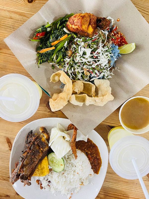 The image features a vibrant Malaysian meal consisting of nasi kerabu and additional dishes.