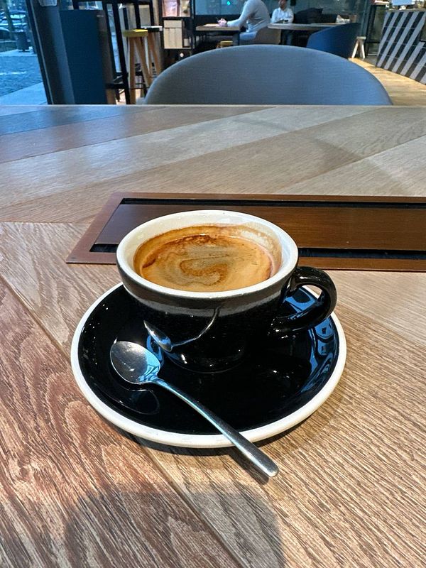 A close-up of a cup of coffee on a wooden table.