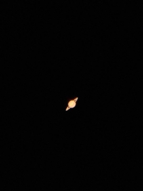 A photograph of the planet Saturn captured through a telescope, showing its rings clearly.