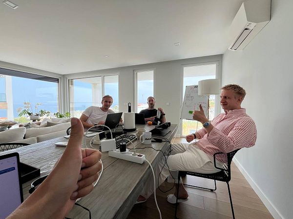 A group of three men is engaged in a coworking session in a bright, modern space.