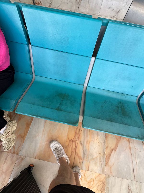 The image captures a dirty seating area at Lisbon Airport, highlighting its neglected condition.