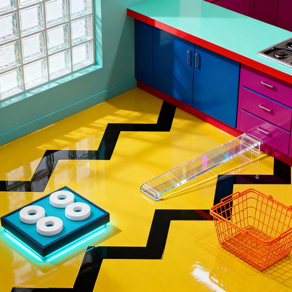 A brightly colored laundry room showcases a high-gloss yellow floor with a bold black zigzag graphic. Along one wall, a turquoise countertop with red edging sits over cobalt blue cabinets and magenta drawers with chrome pulls, near a stainless inset cooktop; sunlight washes through a glass-block window, highlighting a neon-lit platform holding white rolled items, a clear acrylic bench on the floor, and an orange wire laundry basket.
