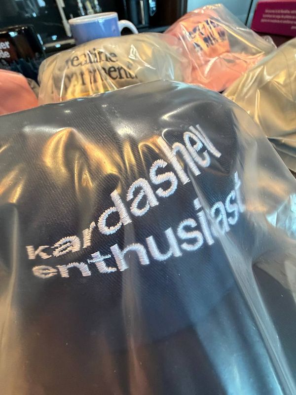 A collection of caps featuring humorous and trendy phrases, prominently displaying 'kardashian enthusiast'.