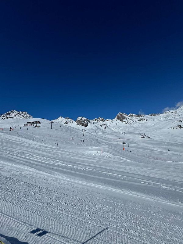 A scenic view of a snowy ski slope under a clear blue sky.