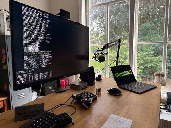 A workspace featuring a large monitor displaying installation progress, a laptop, and various tech equipment.
