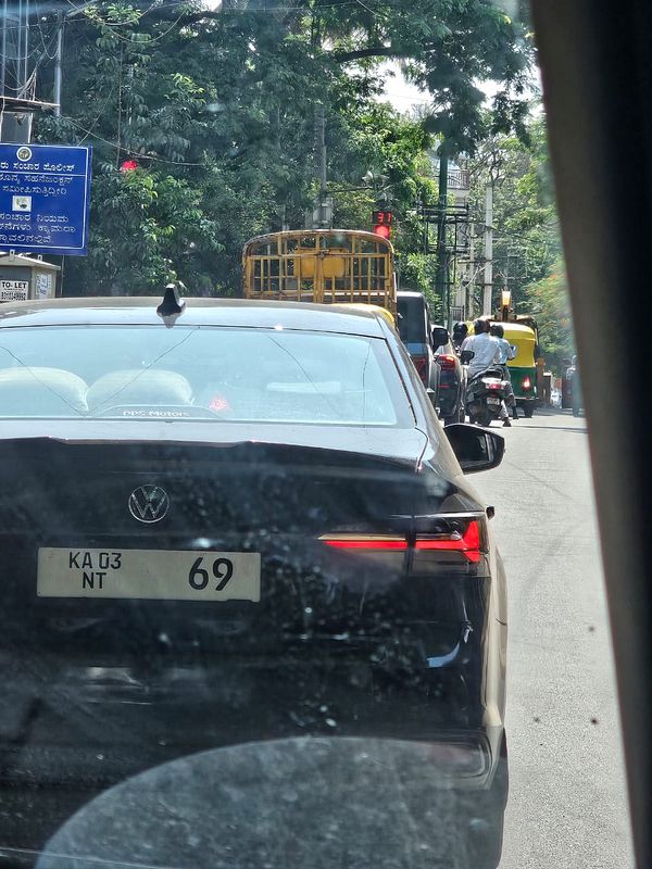 A black Volkswagen car is seen in traffic with a notable number plate.