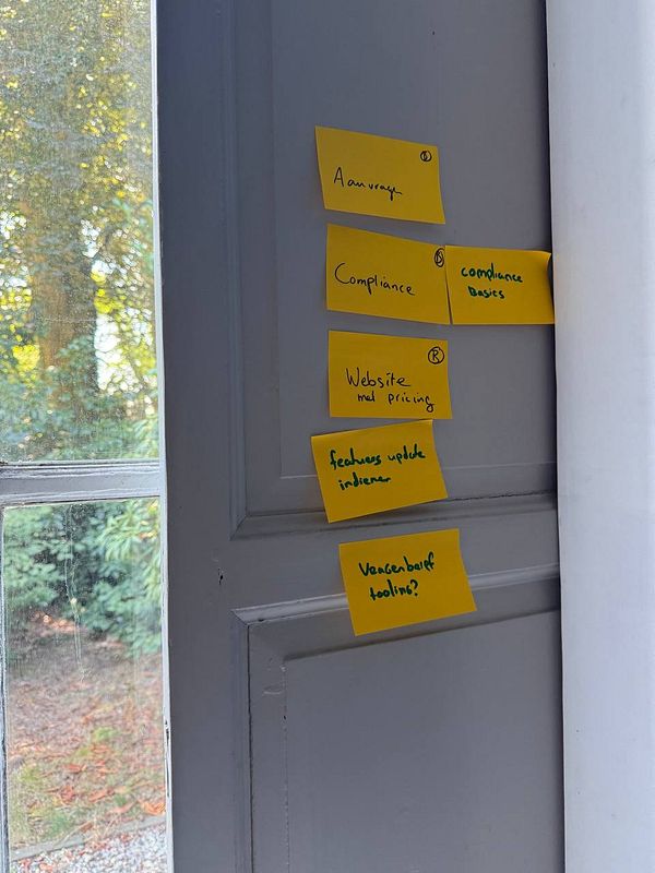 A collection of yellow sticky notes with various tasks and topics is displayed on a door.