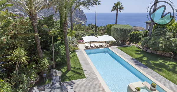 A Mediterranean-style villa with a pool and outdoor living area surrounded by lush greenery.