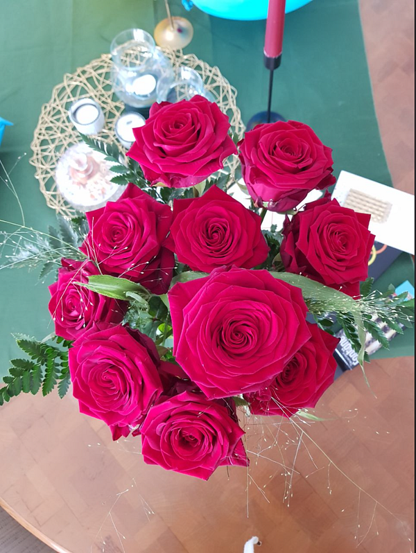 A vibrant bouquet of red roses is prominently displayed on a table.