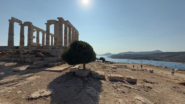 The image captures the ancient ruins of the Temple of Poseidon overlooking a serene coastal landscape.