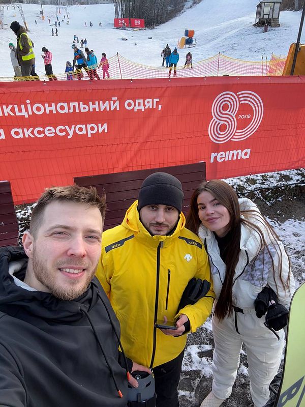 Three individuals pose for a selfie at a ski resort.