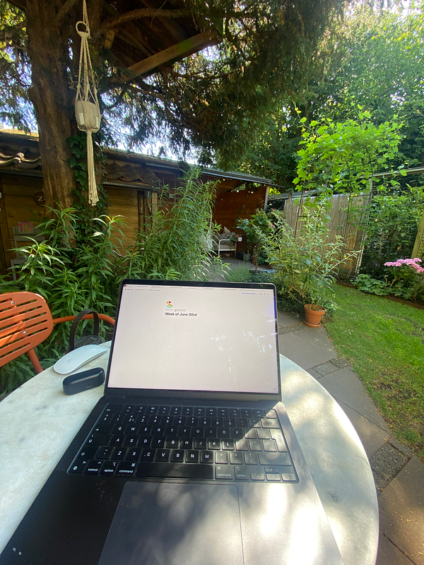 A laptop is set up on a table in a garden, displaying a planning interface.